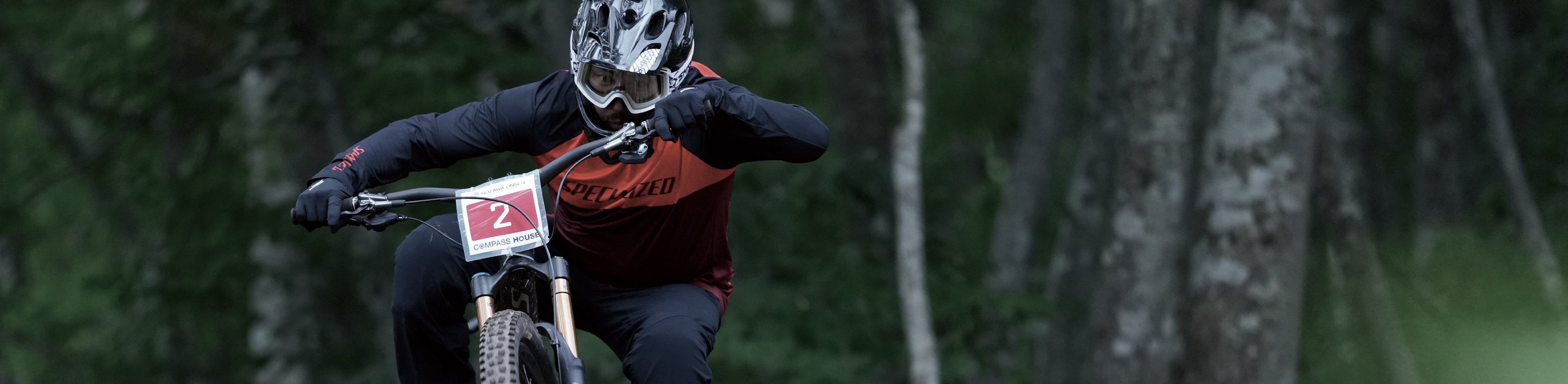 תמונה לדוגמה של רוכב אופנוע תחרותי בתנועה, במוקד עם רקע של יער עם אפקט בוקה