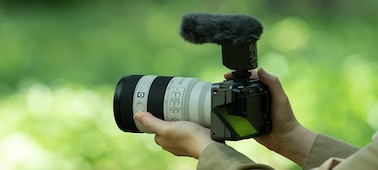 תמונת שימוש המציגה מבט על הצד השמאלי של המצלמה שמוחזקת על ידי משתמש, עם מיקרופון ומגן רוח שמחובר אליו