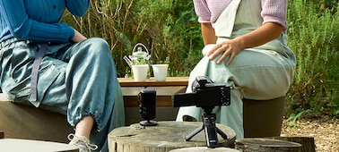 תמונת שימוש של שני אנשים שיושבים בחוץ ומולם מיקרופון. בקרבת מקום נראית מצלמה עם מגבר מחובר