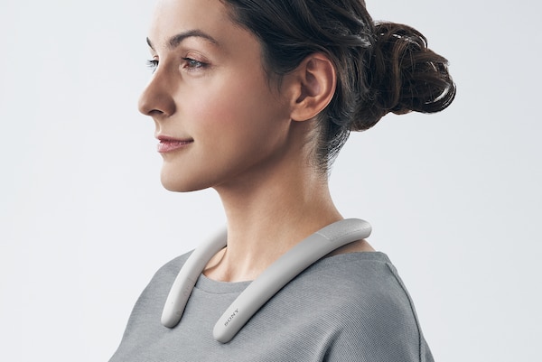 אישה המרכיבה רמקול אלחוטי עם רצועת צוואר SRS-NB10 בלבן