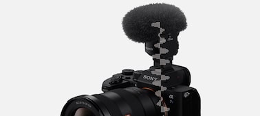 תמונת מוצר שמציגה מבט שמאלי עליון על המצלמה עם מיקרופון ומגן רוח מחוברים, עם איור גרפי של צורת גל דיגיטלית שעוברת מהמיקרופון למצלמה