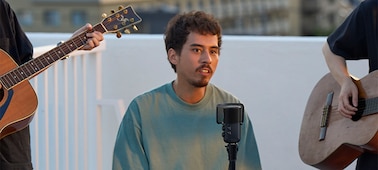 תמונת שימוש של גבר שר עם מיקרופון ומשני צדדיו אנשים מנגנים בגיטרה