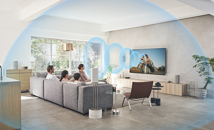 כל המשפחה יושבת על הספה וצופה בטלוויזיה עם מערכת קולנוע ביתי HT-A9 על גבי שידה מעץ, כאשר המסך פולט גלי קול.