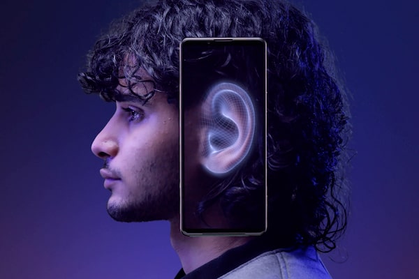 תמונה מהצד של אדם עם טלפון נייד צמוד לאוזן. מסך הטלפון מציג את האוזן עם הילה כחולה מסביבה