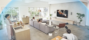 משפחה בסלון צופה בהופעת מוזיקה בטלוויזיה עם מערכת קולנוע ביתי HT-A9 על גבי שידה מעץ עם כיפה של גלי קול