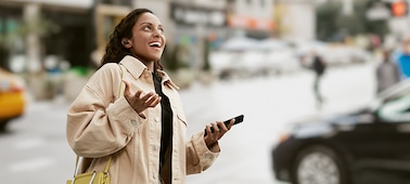 אישה מרכיבה אוזניות LinkBuds S בזמן שהיא הולכת בעיר ומשוחחת בטלפון החכם שלה