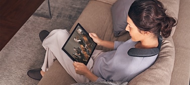 אישה יושבת על ספה וצופה בסרט בטאבלט בעזרת רמקול לביש SRS-NS7