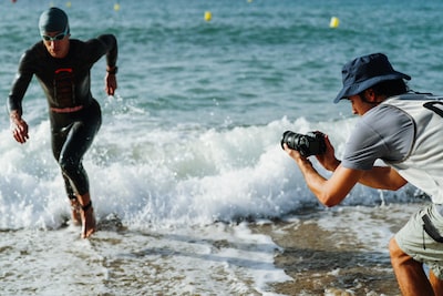 תמונת שימוש של אדם המחזיק במצלמה כדי לצלם טריאתלט רץ אל מחוץ למים