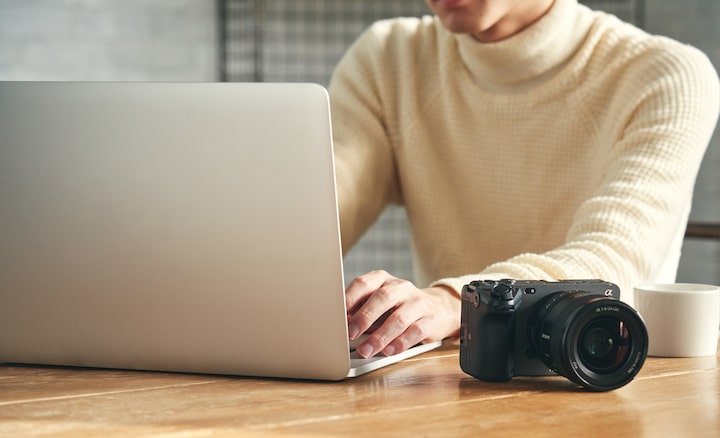 תמונה של אדם יושב ליד שולחן, עובד על מחשב כשהמצלמה מונחת על השולחן
