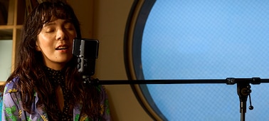 תמונת שימוש של אישה שרה עם מיקרופון שמחובר למעמד זרוע Boom