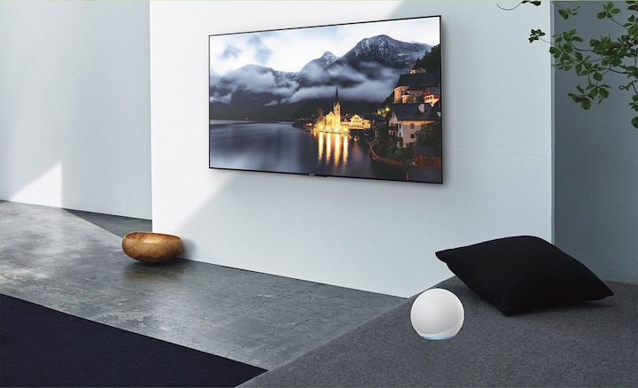סצנת סלון המציגה טלוויזיה על הקיר עם התקן Alexa בצד