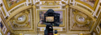 תמונה המציגה מבט אחורי על מצלמה על חצובה בבניין היסטורי עם תמונה על צג LCD וכבל המחובר למצלמה