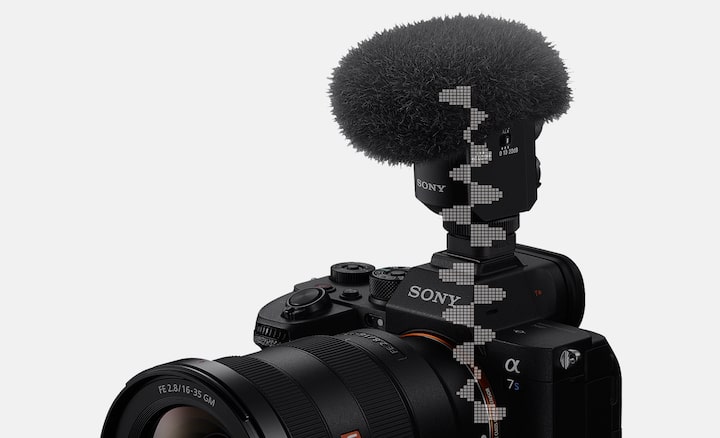 תמונת מוצר שמציגה מבט שמאלי עליון על המצלמה עם מיקרופון ומגן רוח מחוברים, עם איור גרפי של צורת גל דיגיטלית שעוברת מהמיקרופון למצלמה