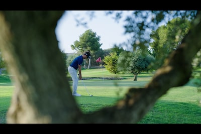 תמונה לדוגמה המציגה מיקוד על שחקן גולף עם מראה מטושטש של גזע עץ ברקע