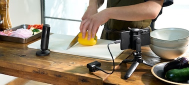 תמונת שימוש המציגה האם מבשל ולצידו מוצב המיקרופון, והמגבר מחובר בעזרת כבל USB לטלפון חכם על מעמד
