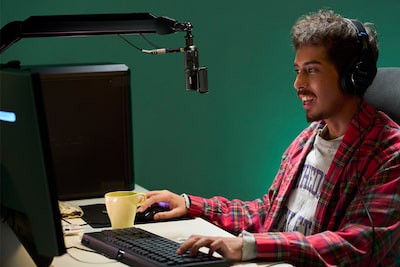 תמונת שימוש של גבר יושב מול צג של מחשב ומרכיב אוזניות שמחוברות על ידי כבל למיקרופון