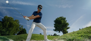 תמונה לדוגמה של שחקן גולף שר לפני חבטה בכדור מעל מכשול