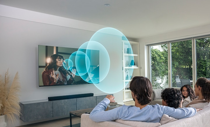 משפחה צופה בטלוויזיה בסלון עם גלי קול בוקעים מהמסך