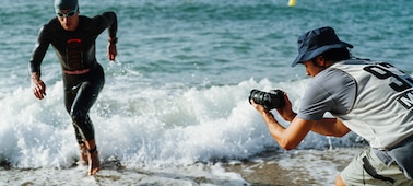 תמונת שימוש של אדם המחזיק במצלמה כדי לצלם טריאתלט רץ אל מחוץ למים