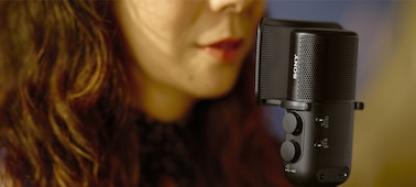 תמונת שימוש שמציגה אישה שרה, הפה שלה קרוב למיקרופון שאליו מחובר מגן חוצץ