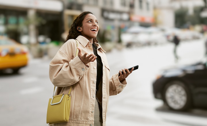 אישה מרכיבה אוזניות LinkBuds S בזמן שהיא הולכת בעיר ומשוחחת בטלפון החכם שלה