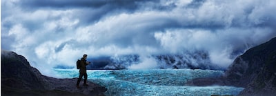 תמונה המראה משתמש מחזיק מצלמה בסביבה הררית פראית עם ערפל, עננים ושדה קרח