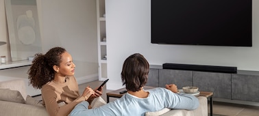 משפחה שנהנית ממוזיקה בסלון עם טלוויזיה ומקרן הקול HT-A5000 על ארונית שיש