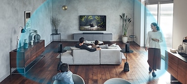 משפחה צופה בטלוויזיה בסלון מרווח. כיפה כחולה מדגימה את אזור ההאזנה הרחב של צליל מרחבי 360.