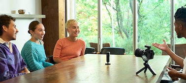 תמונת שימוש של מיקרופון שמוצב במרכז שולחן וסביבו ארבעה אנשים משוחחים
