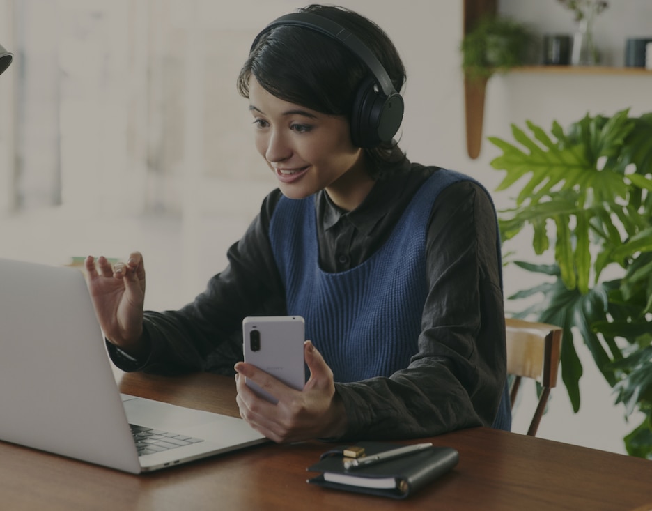 Image of a person having an online chat using Sony Wireless headphone and a mobile phone