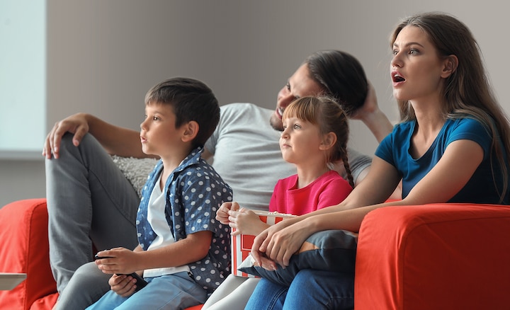 משפחה צופה בטלוויזיה מהספה