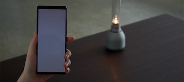 רמקול הזכוכית LSPX-S3 של Sony וטלפון חכם, להדגמה כיצד ניתן לנהל את המוצר באמצעות האפליקציה